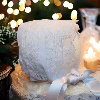 Boné branco bordado com fita de cetim num ambiente decorado com velas e luzes
