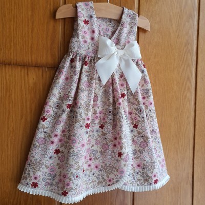 Vestido floral de criança com laço branco pendurado em cabide
