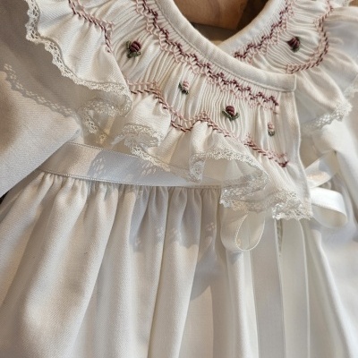 Vestido branco com bordados florais em cabide de madeira