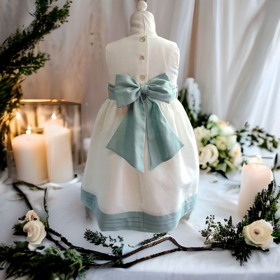 Vestido branco com laço azul claro num manequim, decorado com velas e flores