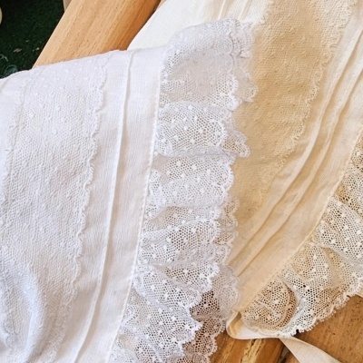 Peças de roupa branca com renda sobre madeira clara