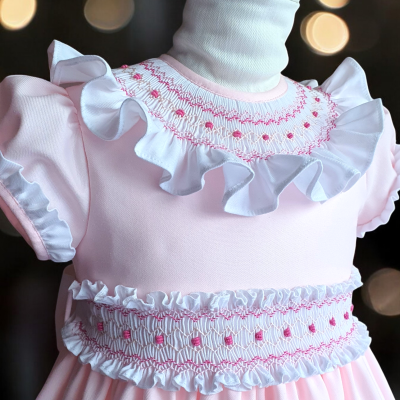 Vestido infantil rosa com folhos e bordados em exposição num manequim