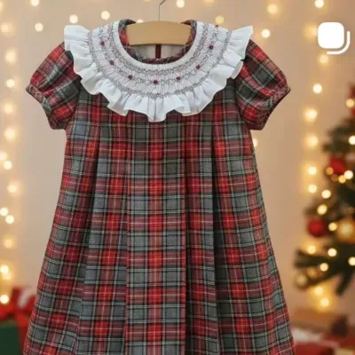 Vestido infantil xadrez vermelho e cinzento com gola bordada branca em ambiente festivo