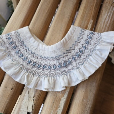 Gola branca bordada com folhos sobre madeira