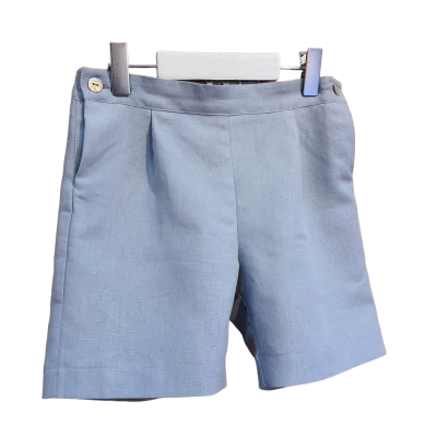 Calções de criança azuis claros com botão prateado pendurados num cabide