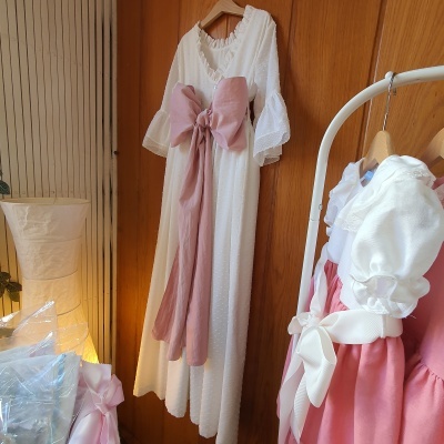 Vestido branco com grande laço rosa pendurado num cabide