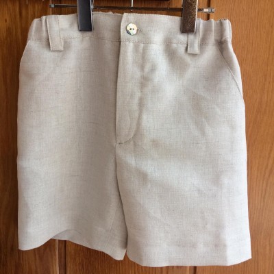 Calções beges claros suspensos em cabides de madeira