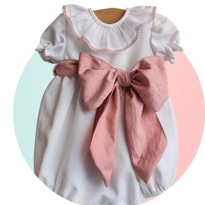Vestido branco de bebé com laço rosa grande e gola com folhos cor-de-rosa