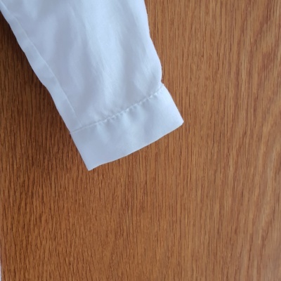 Manga de camisa branca em superfície de madeira clara