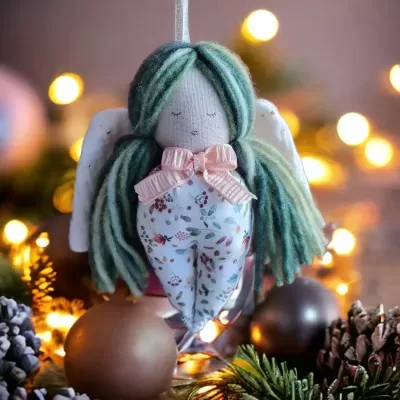 Boneco anjo decorativo com cabelo de lã verde e roupa floral pendurado em decoração festiva