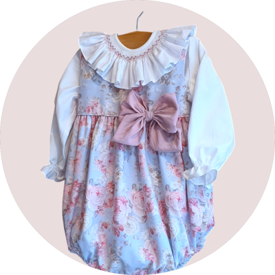 vestido de criança azul claro com padrão floral rosa, mangas brancas e laço rosa