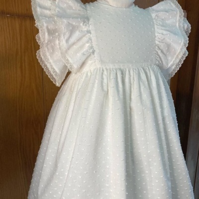 Vestido branco de criança com folhos e textura de pontos