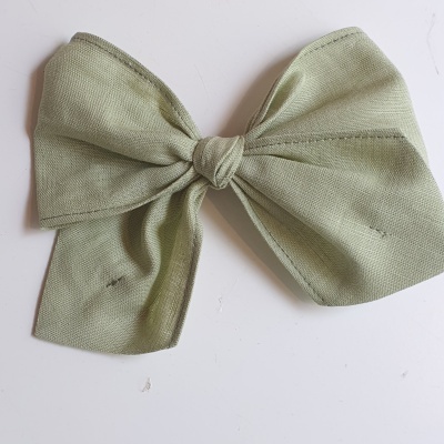 Laço verde claro em tecido com textura rugosa sobre superfície branca