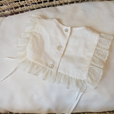 Gola branca com botões e renda sobre tecido branco texturizado