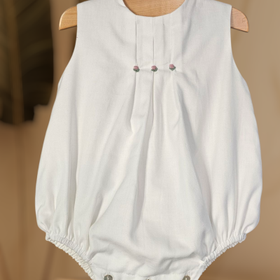 Body de bebé branco com botões e elástico, em cabide de madeira.