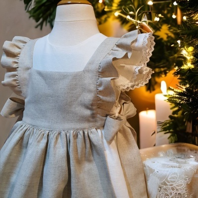 Vestido de criança bege com mangas franzidas junto a decoração de Natal