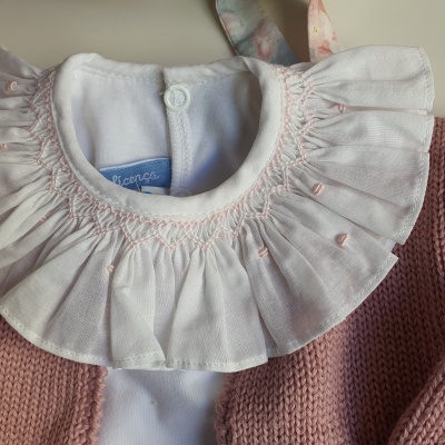 Gola branca franzida de roupa infantil com malha rosa e etiqueta azul