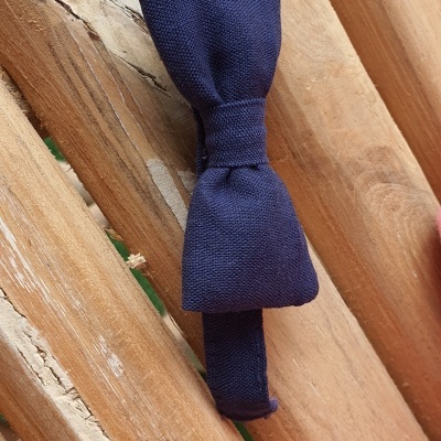 Gravata borboleta azul escuro sobre ripas de madeira clara