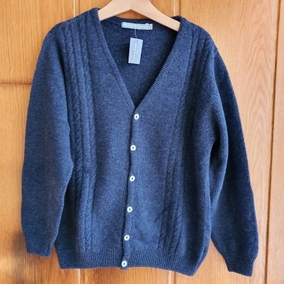 Cardigan azul-escuro de lã com botões brancos pendurado em cabide de madeira