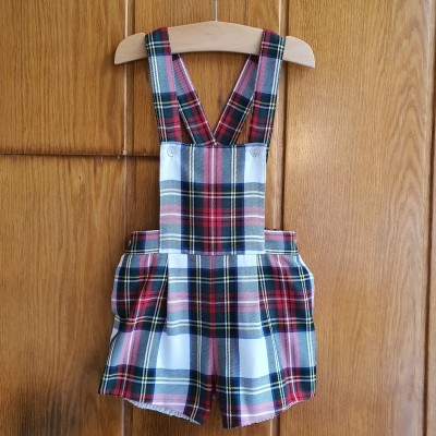 Macacão curto para criança em xadrez colorido, pendurado num cabide