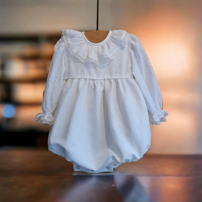 Macacão branco para bebé com gola e punhos com folhos em fundo desfocado