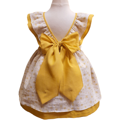 Vestido de bebé branco com padrão amarelo e grande laço amarelo atrás