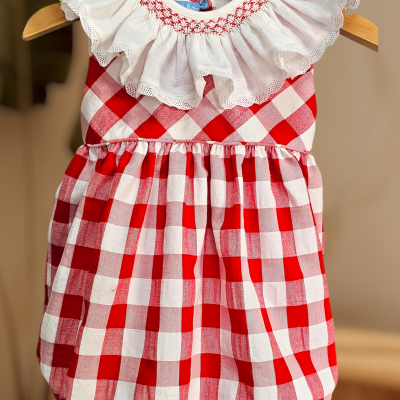 Vestido de bebé vermelho e branco com gola branca bordada pendurado