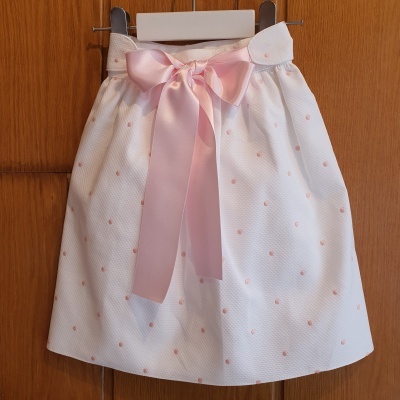 Saia branca com pontos rosa e laço rosa pendurada