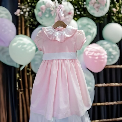 Vestido infantil rosa com gola branca e balões coloridos ao fundo