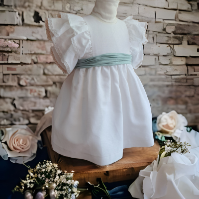 Vestido infantil branco com faixa verde água exposto em manequim