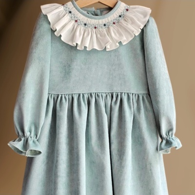 Vestido infantil azul claro com gola branca bordada pendurado