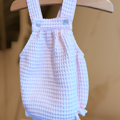 Macacão de bebé branco com textura e alças pendurado num cabide