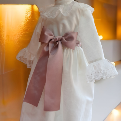 Vestido branco de bebé com laço rosa e detalhes em renda