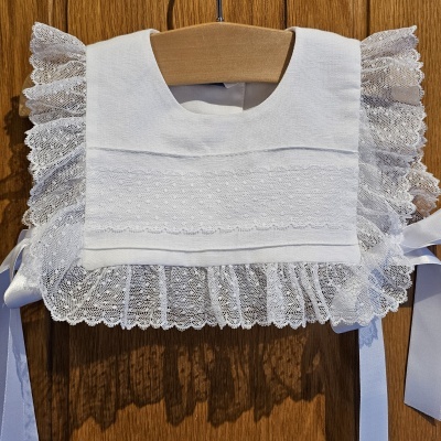 Bolero branco com renda pendurado em cabide de madeira