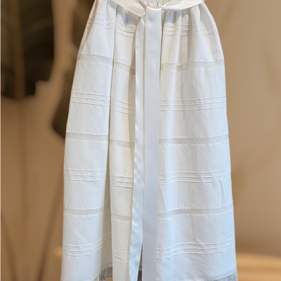 Saia branca com cinto largo de cetim, bandas horizontais e bordado rendado na barra.