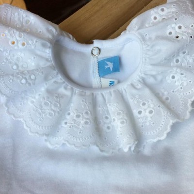 Camisola branca de bebé com gola de renda branca e botão na gola