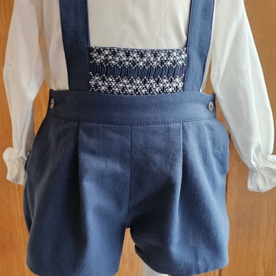 Conjunto infantil azul e branco em manequim diante de fundo de madeira