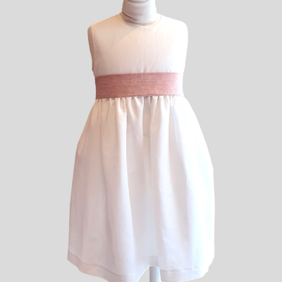Vestido infantil branco com faixa rosa ao redor da cintura, em manequim