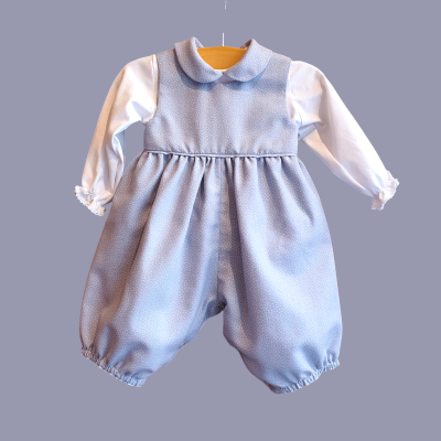 Roupa de bebé lilás com pontos brancos e mangas compridas brancas pendurada