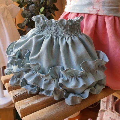 Bloomers azul claro com babados e cintura elástica sobre madeira