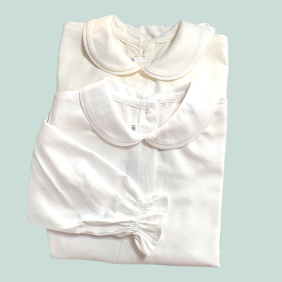 Dois bodies de bebé brancos com gola redonda, um de manga comprida com punho elástico e outro de manga curta.