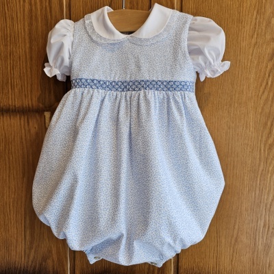 Vestido infantil azul claro com padrão floral e gola branca