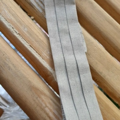 Correia de tecido cinza claro com linhas verticais pretas sobre madeira clara