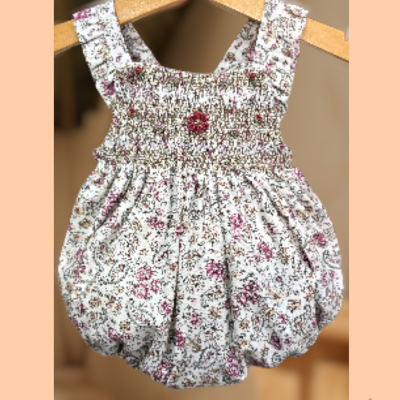 Macacão de bebé floral em tecido leve pendurado num cabide