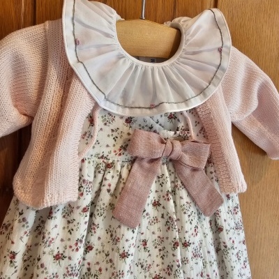 Conjunto de vestido floral, casaco rosa e gola branca em cabide de madeira