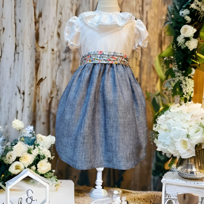 Vestido infantil branco e azul com faixa floral exposto em manequim