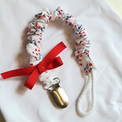 prendedor para chucha branco com estampado floral e laço vermelho