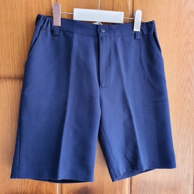 Calções azul escuro com textura pendurados numa porta de madeira