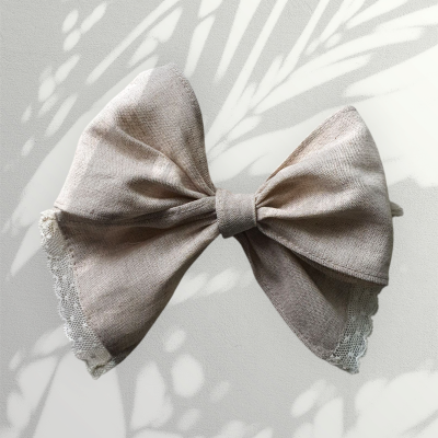 Laço de cabelo bege com renda branca e sombras de folhas