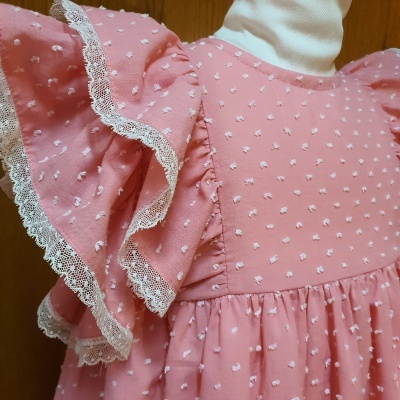 Vestido rosa de criança com bordados brancos, rendas e folhos